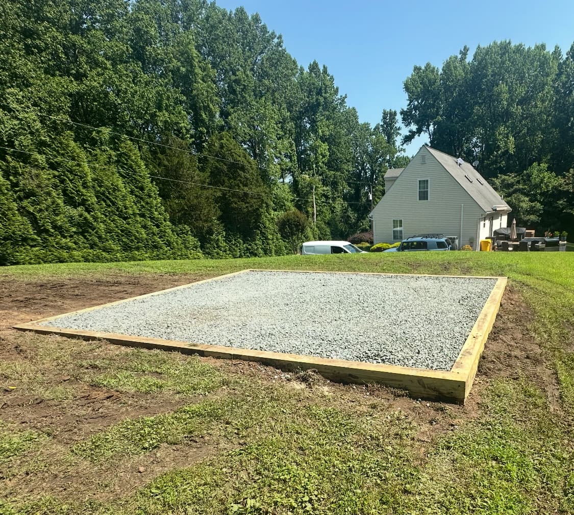 Large crushed stone gravel pad on open residential lot in summer