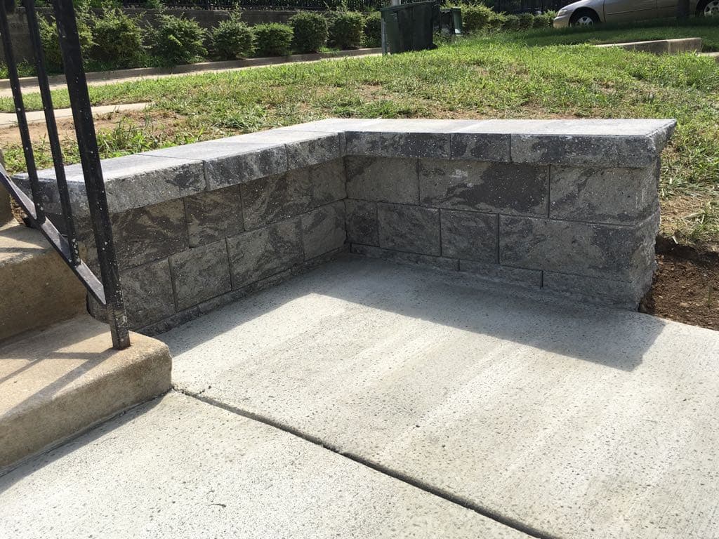Close-up of stone block retaining wall corner with concrete broom finish