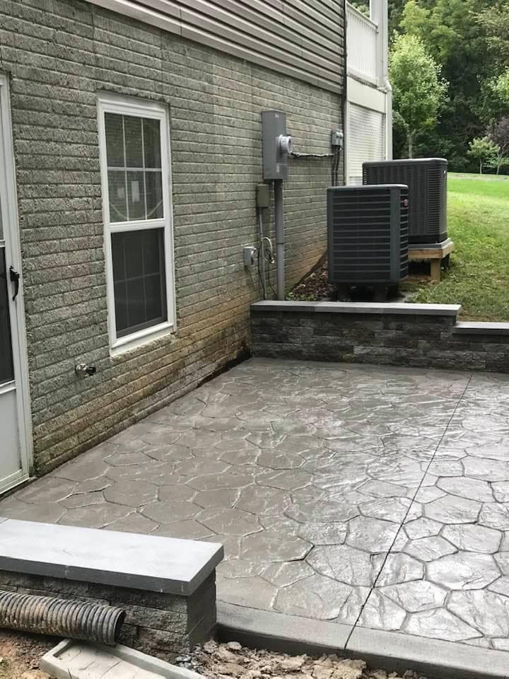 Stamped concrete patio with flagstone pattern and stone block wall