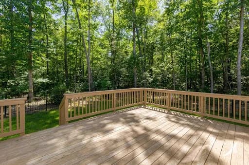 Custom wood deck with railing overlooking wooded backyard in Anne Arundel County